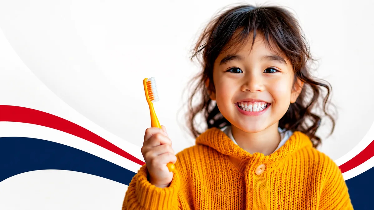 A smiling child holding a toothbrush at Warren Dental Associates